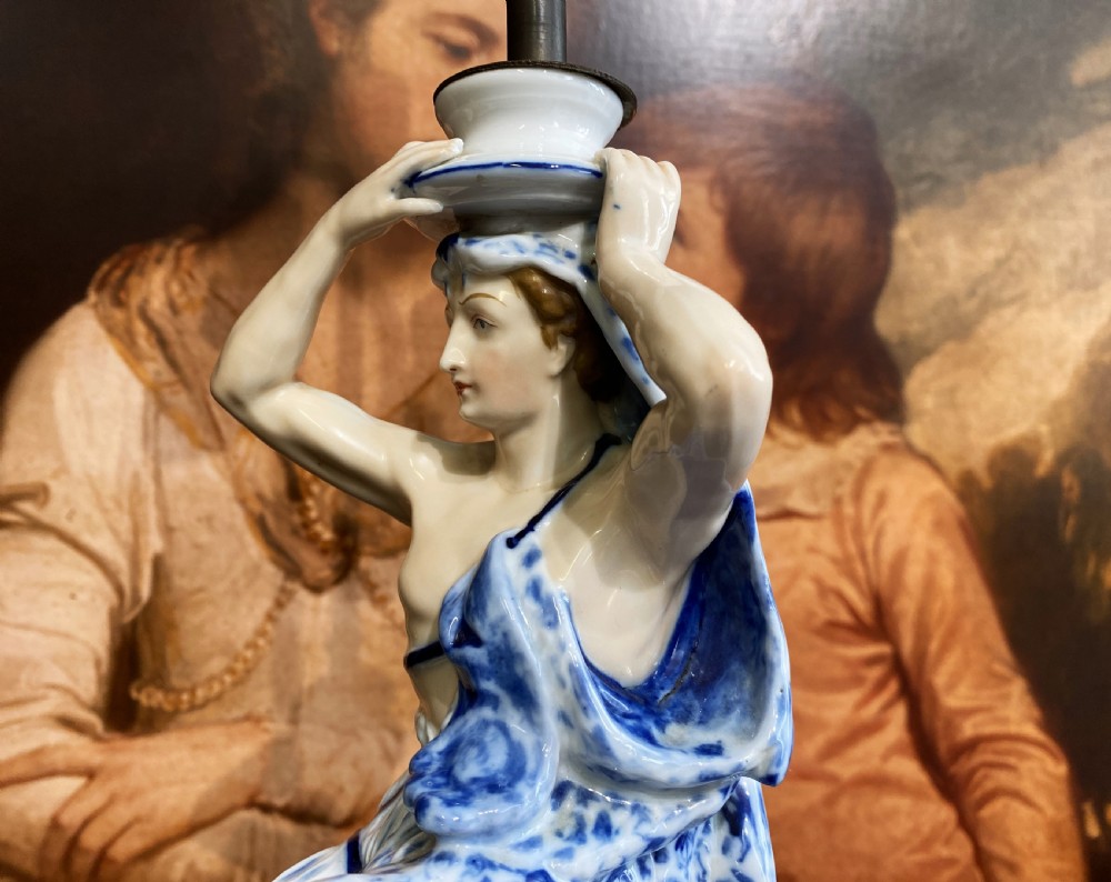 An Art Deco blue and white porcelain table lamp featuring a sculpted male figure on a decorative pedestal with a twin brass light socket stem. View XII