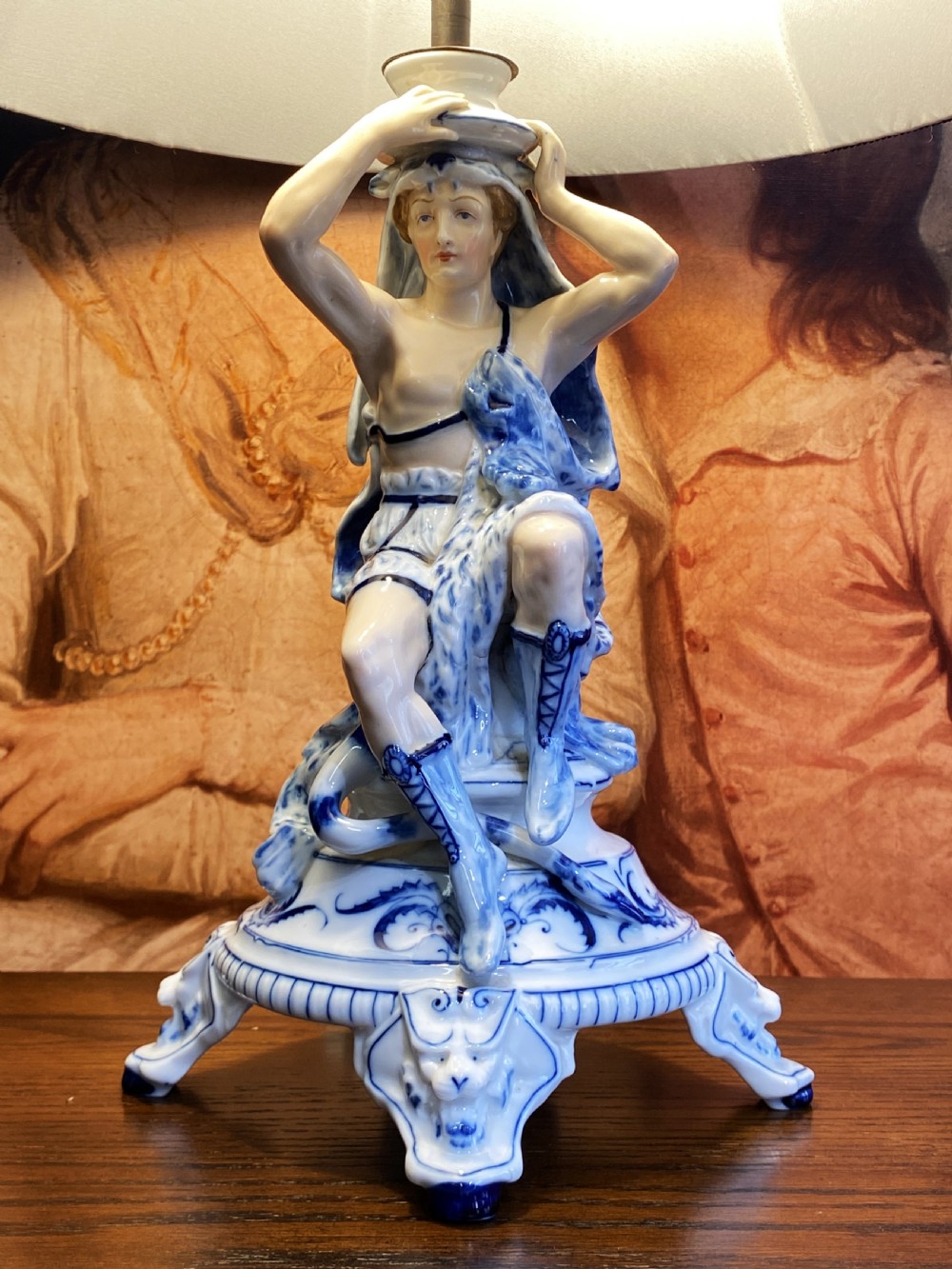 An Art Deco blue and white porcelain table lamp featuring a sculpted male figure on a decorative pedestal with a twin brass light socket stem. View XVI