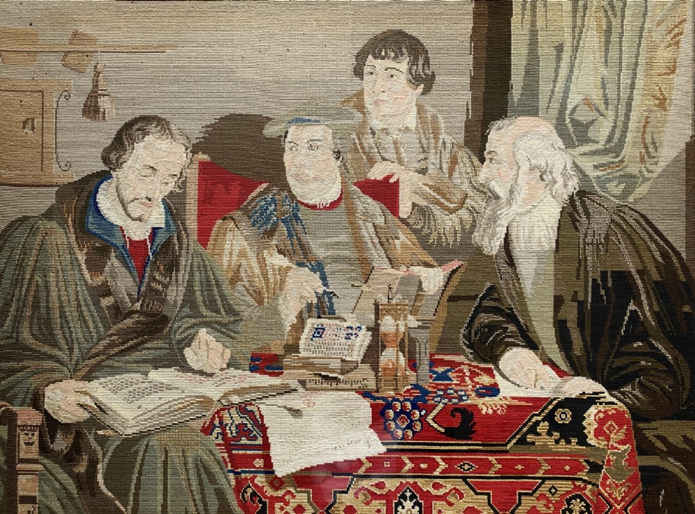 A framed mid-nineteenth-century Berlin woolwork tapestry depicting four historical figures seated around a carpet-covered table, housed within a gilt decorative frame. View III