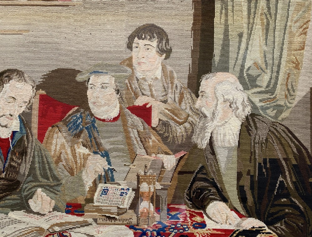 A framed mid-nineteenth-century Berlin woolwork tapestry depicting four historical figures seated around a carpet-covered table, housed within a gilt decorative frame. View IV