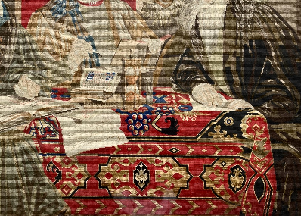 A framed mid-nineteenth-century Berlin woolwork tapestry depicting four historical figures seated around a carpet-covered table, housed within a gilt decorative frame. View V