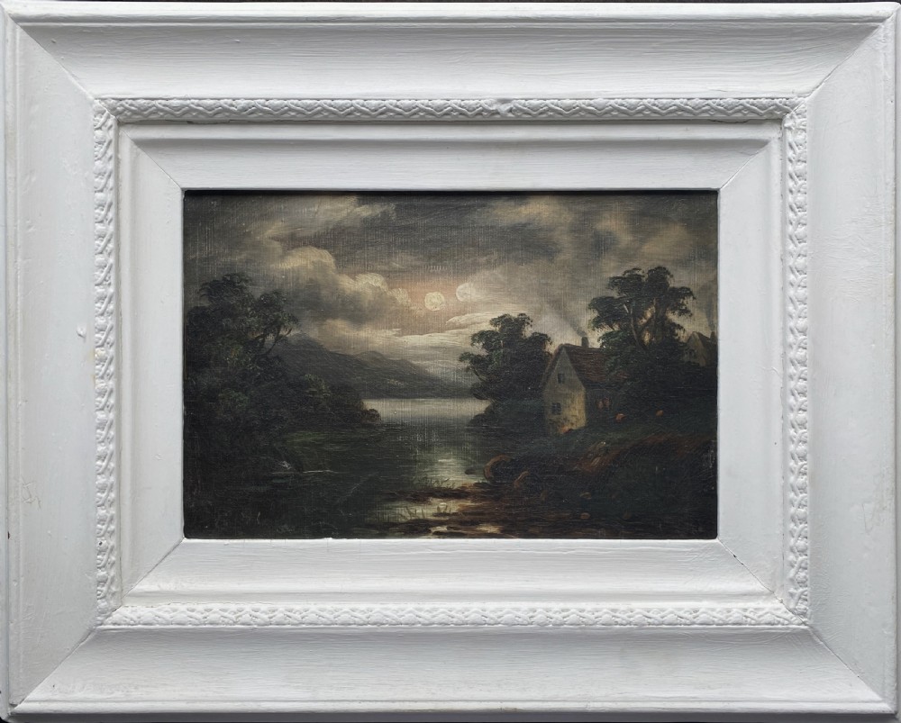 An oil painting depicting a moonlit highland loch scene with a small cottage near the water, framed in a thick white painted wooden frame.
