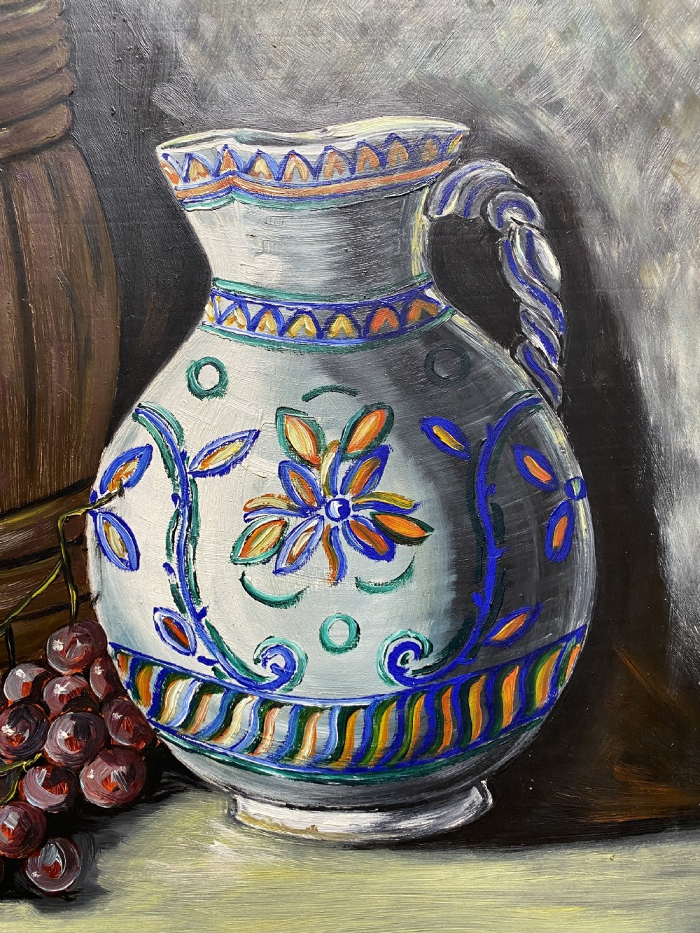 A framed mid-century oil painting depicting a still life composition with a blue patterned ceramic jug, a wooden barrel, a melon slice, and purple grapes. View VI