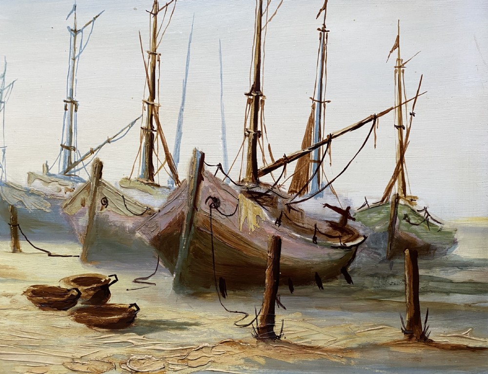 A horizontal mid-century oil painting depicting grounded fishing vessels on a sandy harbour floor beneath a cloudy blue sky, contained within a textured brown frame. View IX
