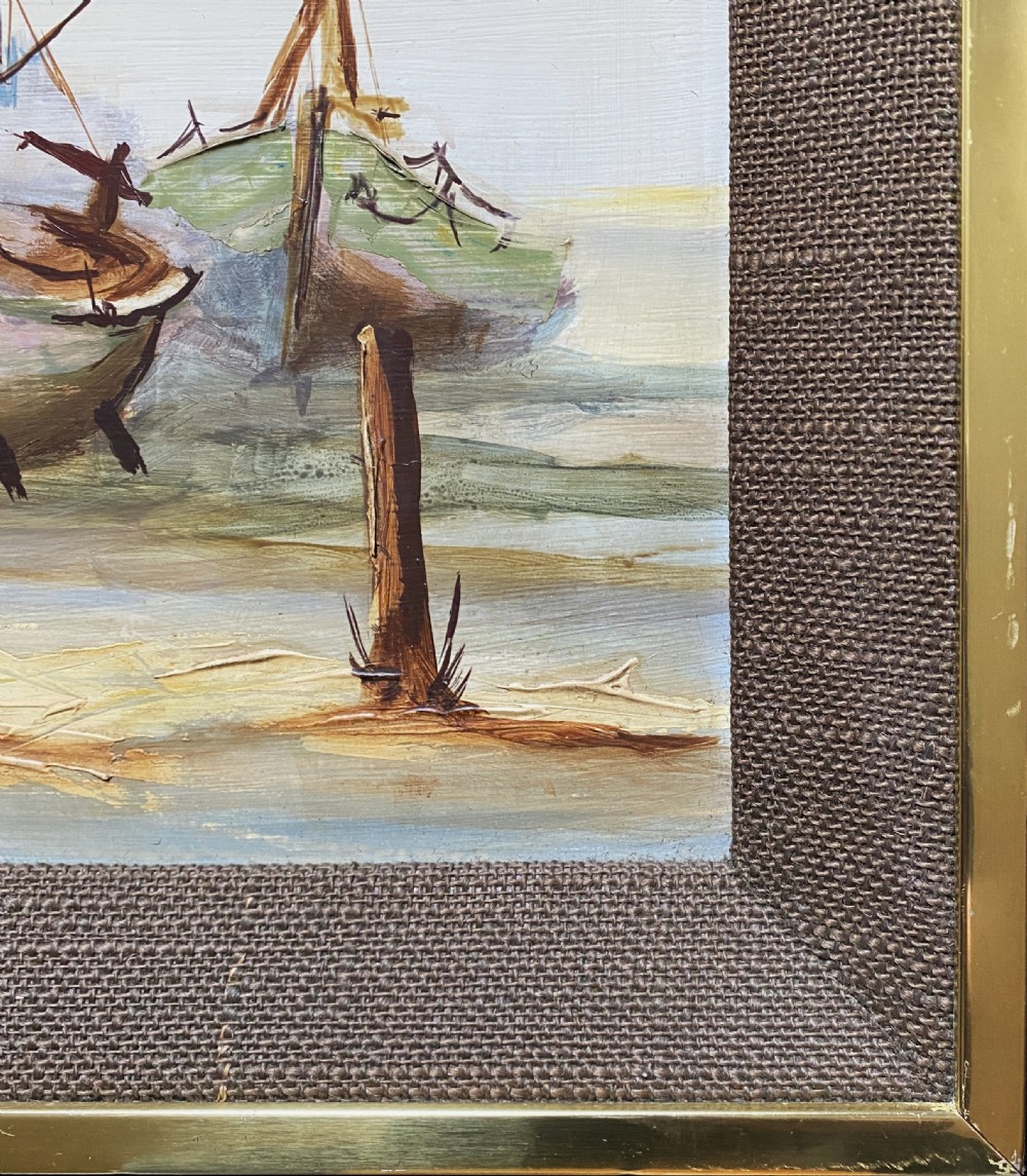 A horizontal mid-century oil painting depicting grounded fishing vessels on a sandy harbour floor beneath a cloudy blue sky, contained within a textured brown frame. View X