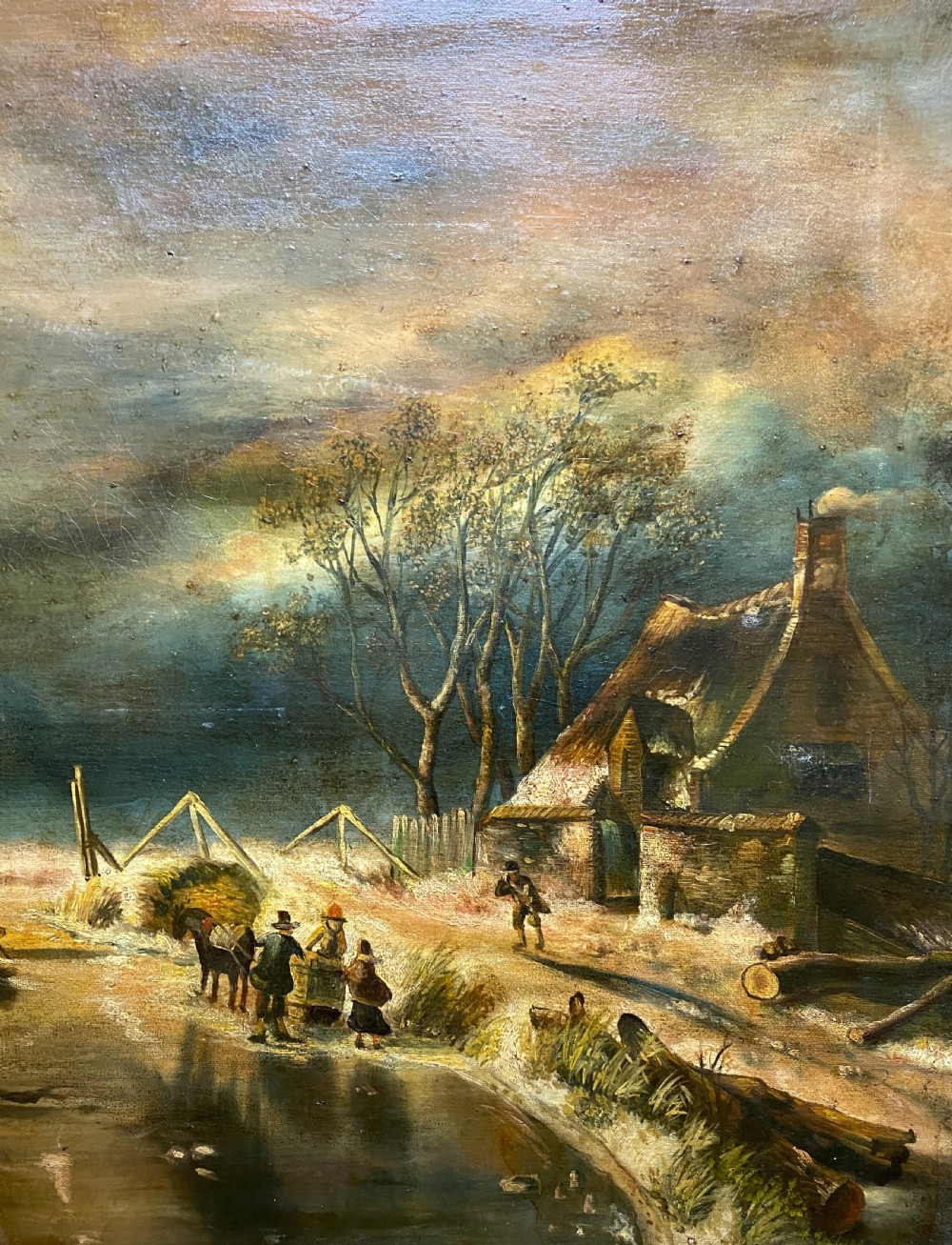 A framed oil painting depicting a nocturnal winter river landscape with figures, a thatched cottage, and a church spire in the background. View V