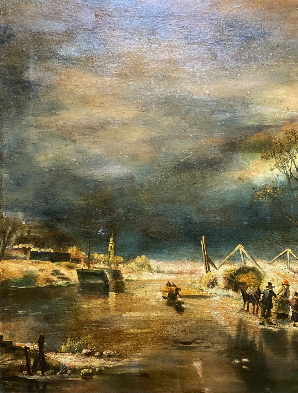 A framed oil painting depicting a nocturnal winter river landscape with figures, a thatched cottage, and a church spire in the background. View VII