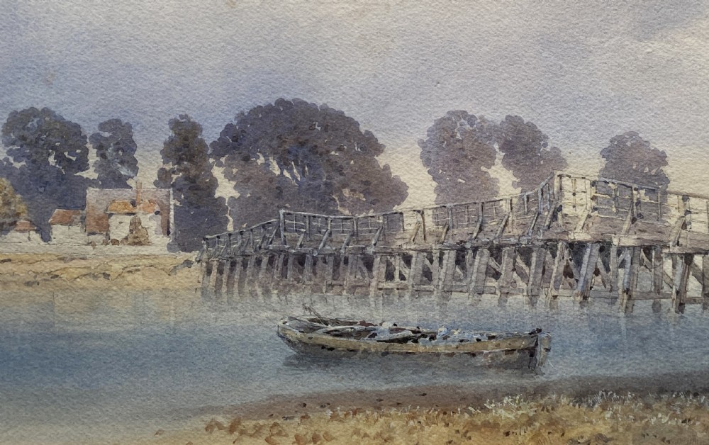 A framed watercolour painting depicting a wooden toll bridge across a river with a small boat and church in the background, set in a gilded frame. View V