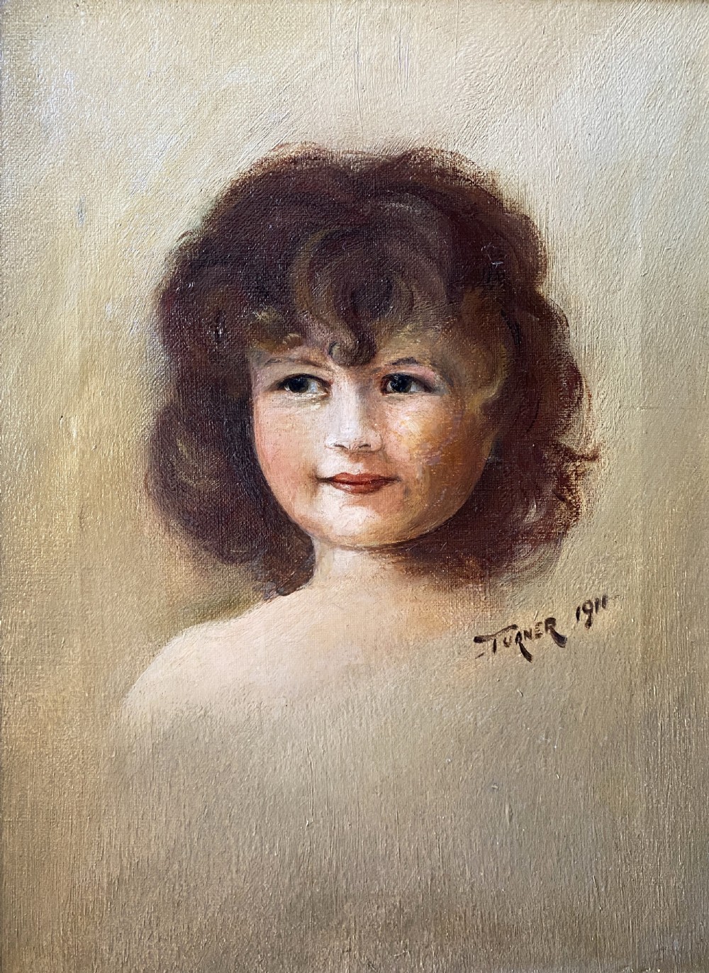 An early twentieth-century oil painting depicting a young girl with brown curly hair, framed within a wide moulded gold gilt frame. View II