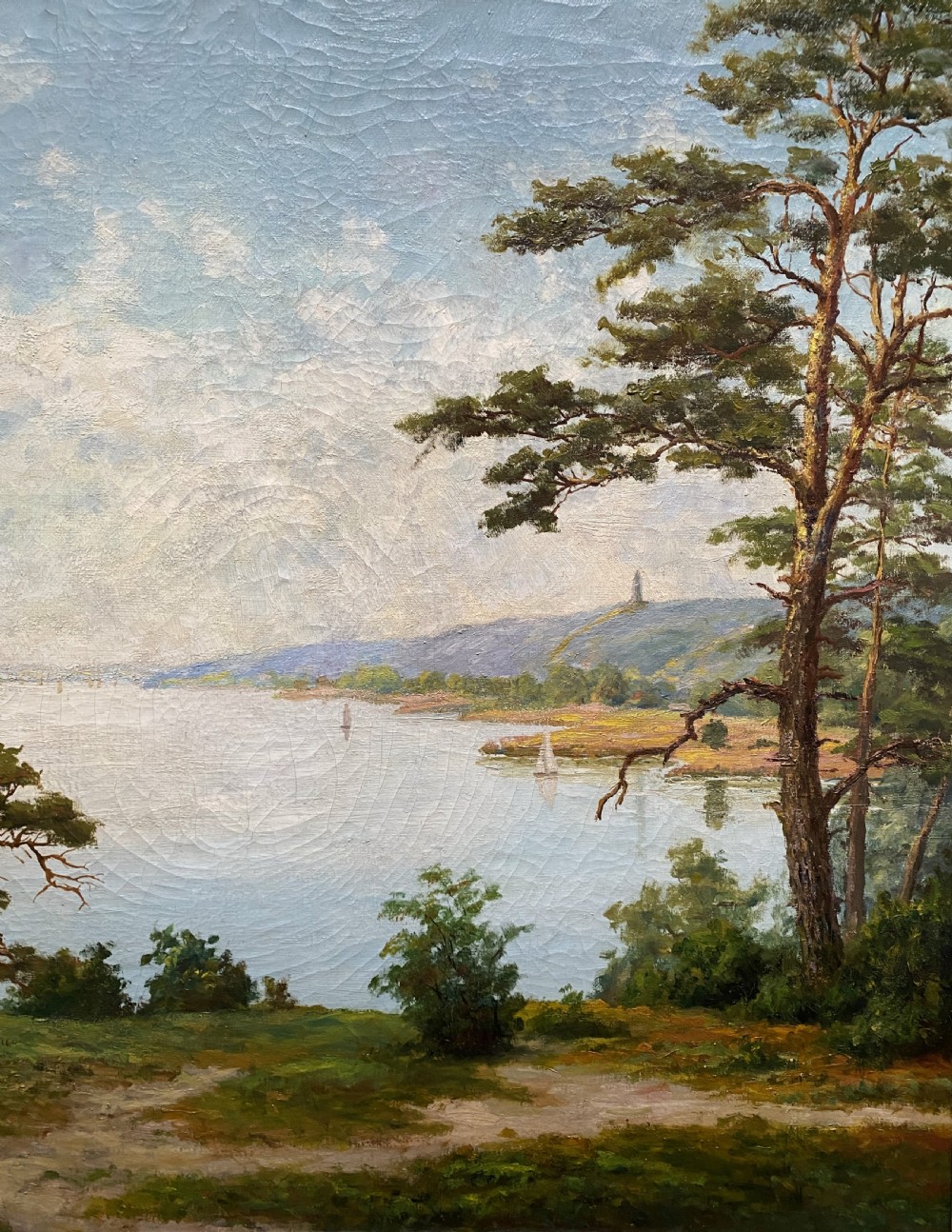 A signed 20th-century oil painting depicting a calm lake with sailboats framed by birch and pine trees in a silvered wooden frame. View III