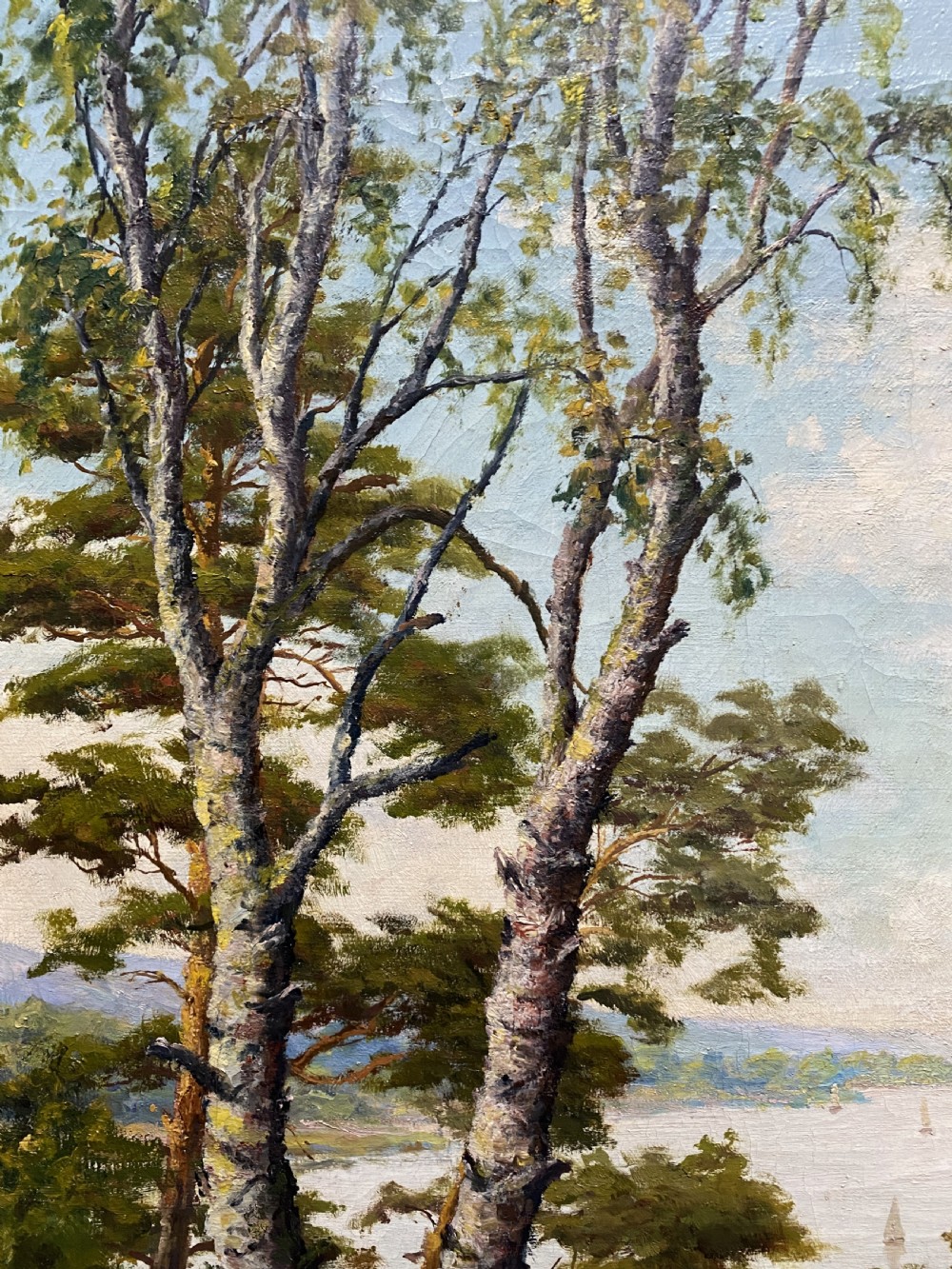 A signed 20th-century oil painting depicting a calm lake with sailboats framed by birch and pine trees in a silvered wooden frame. View IX
