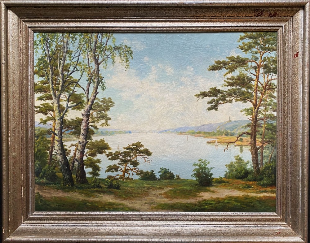 A signed 20th-century oil painting depicting a calm lake with sailboats framed by birch and pine trees in a silvered wooden frame. View XII