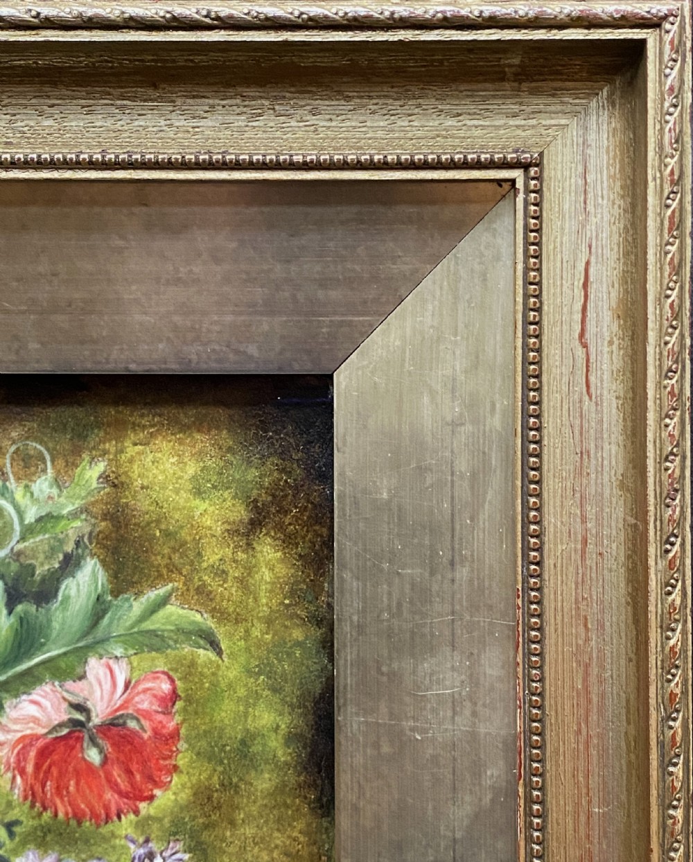 A framed oil painting featuring a floral bouquet in an urn set upon a ledge next to a bird nest. View XI