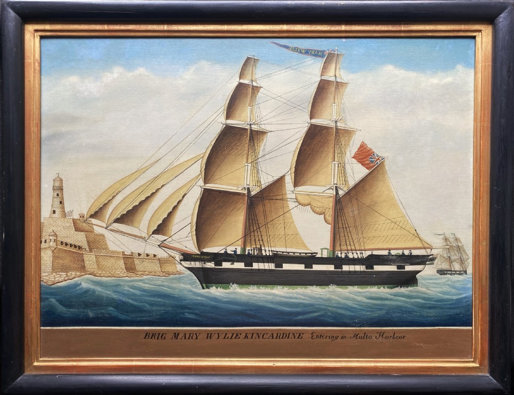 An early 19th-century marine oil painting depicting a two-masted brig ship sailing into Malta harbour, set within a black and gilt wooden frame.
