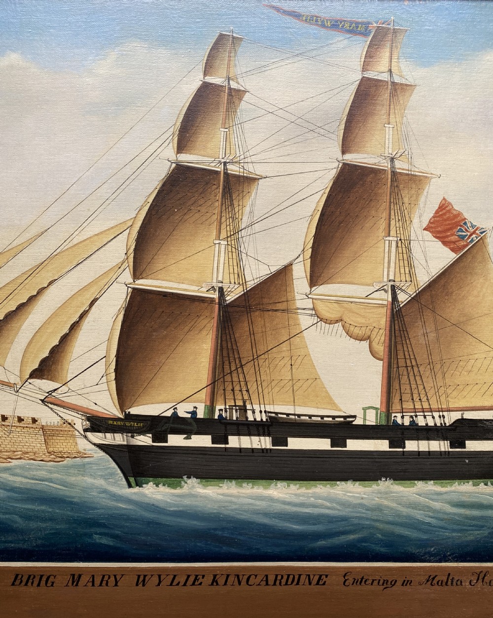 An early 19th-century marine oil painting depicting a two-masted brig ship sailing into Malta harbour, set within a black and gilt wooden frame. View VIII