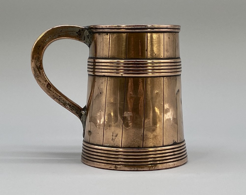 A tapered late Georgian copper tankard featuring horizontal reeded bands, vertical staved lines, and a curved nickel-plated handle. View V