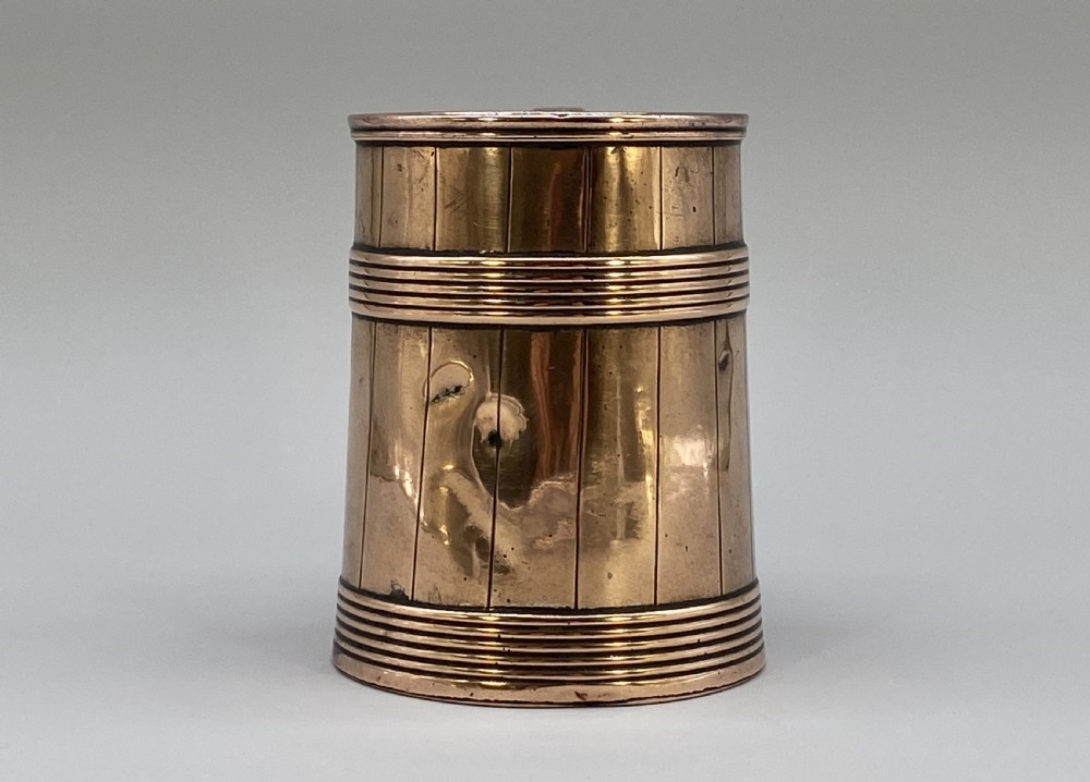 A tapered late Georgian copper tankard featuring horizontal reeded bands, vertical staved lines, and a curved nickel-plated handle. View VI