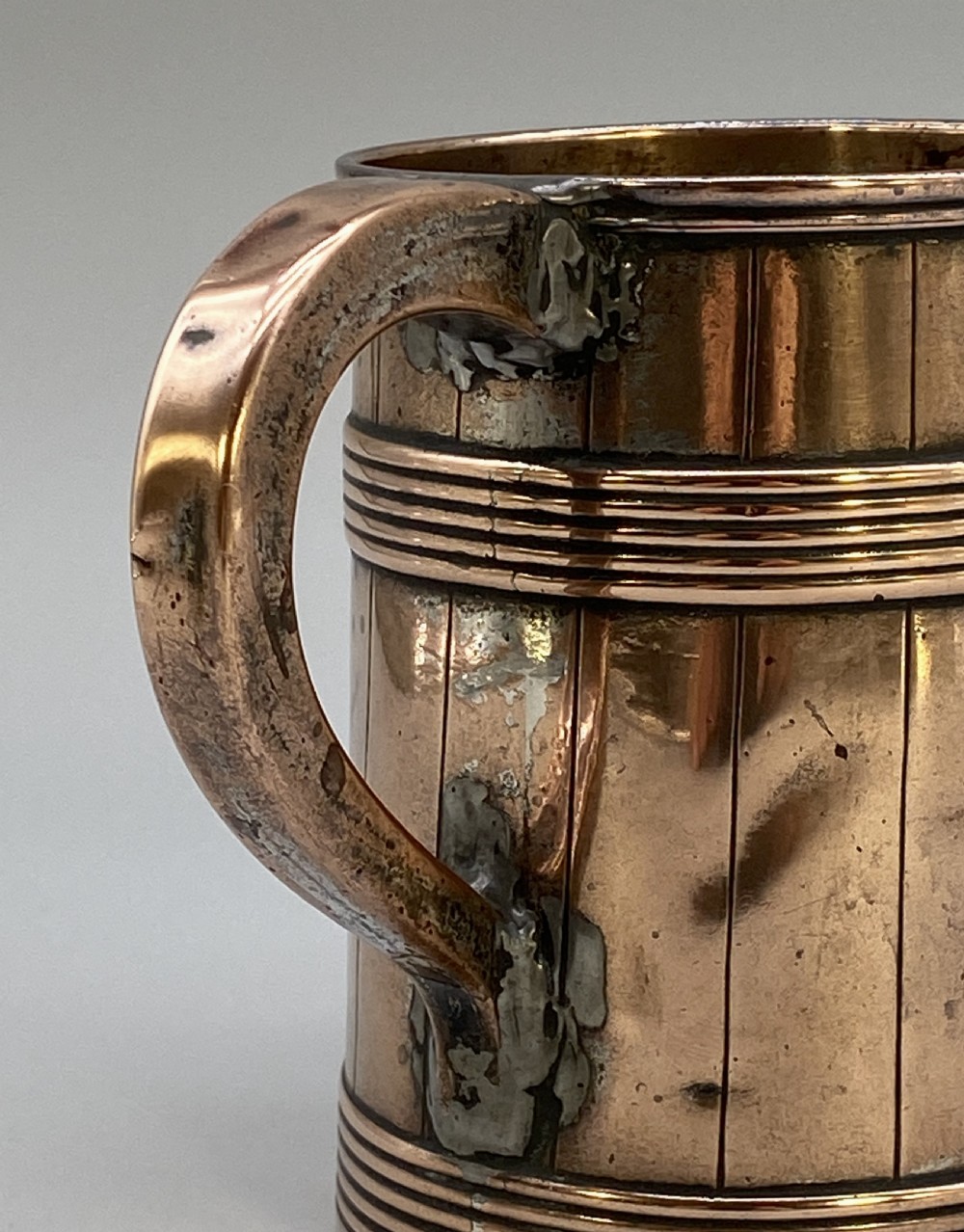 A tapered late Georgian copper tankard featuring horizontal reeded bands, vertical staved lines, and a curved nickel-plated handle. View IX