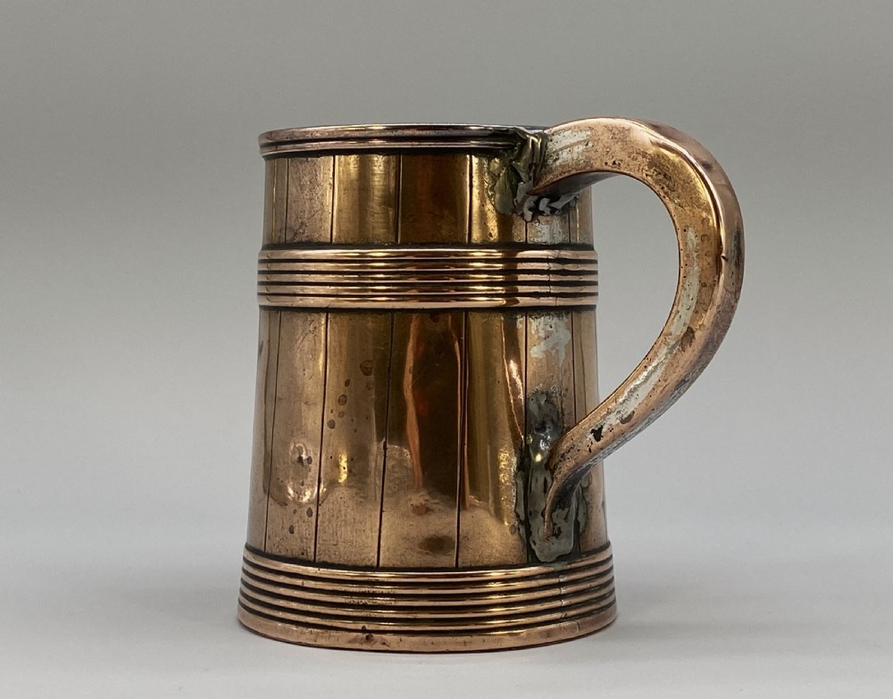 A tapered late Georgian copper tankard featuring horizontal reeded bands, vertical staved lines, and a curved nickel-plated handle. View XVI