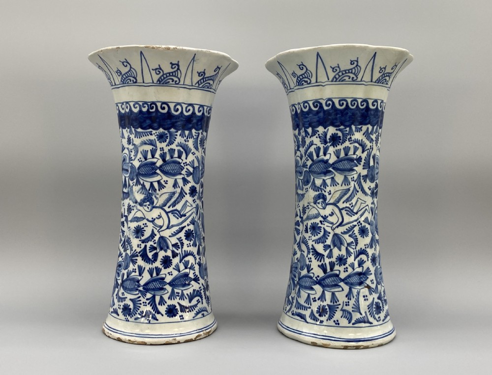 A pair of flared antique Dutch Delftware tin-glazed earthenware beaker vases decorated in cobalt blue and white with floral motifs and winged figures.