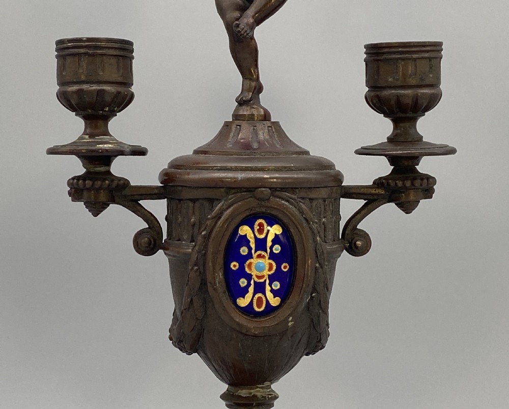 A pair of late 19th-century bronzed spelter twin-light candelabra featuring putti surmounts and urn-shaped bodies set with blue enamel plaques. View VIII