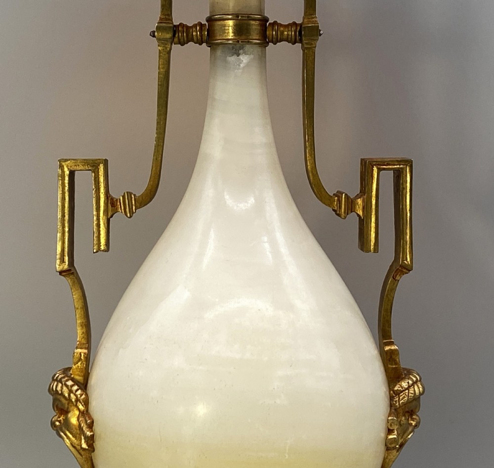 An antique French amphora-shaped white onyx table lamp with gilt metal handles and paw feet, topped with a pleated fabric shade. View IX