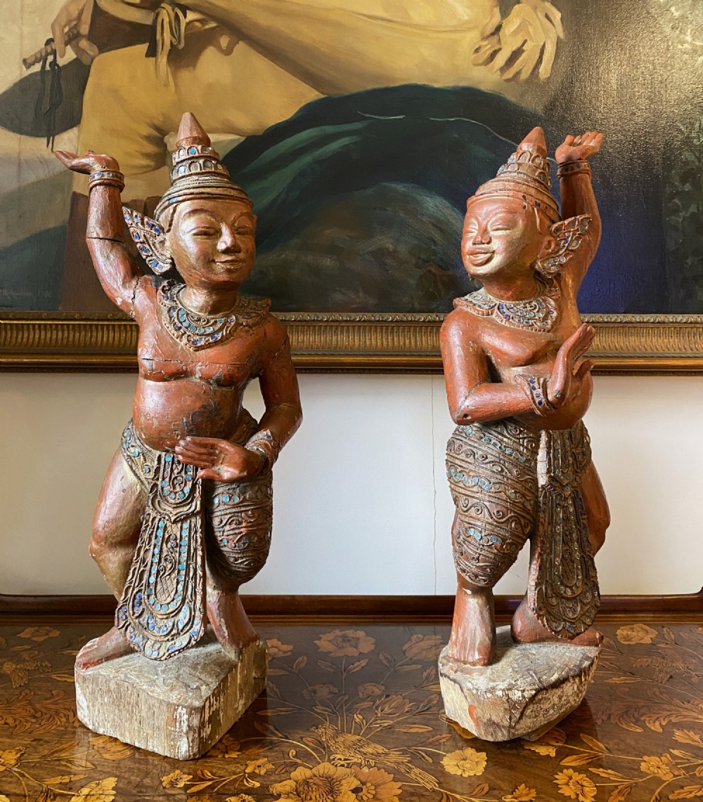 A pair of 19th-century carved wooden Burmese Nat statues featuring a red painted finish, elaborate crowns, and glass mirror inlays.