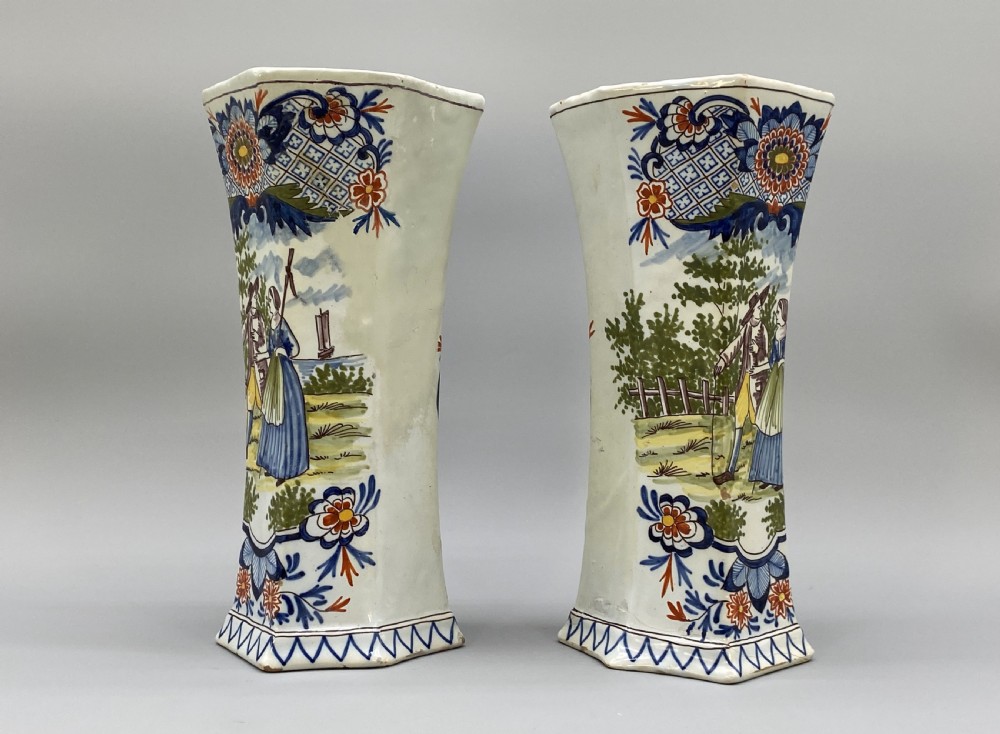 A pair of 18th-century octagonal flared Dutch Delft polychrome tin-glazed earthenware vases featuring hand-painted pastoral scenes of figures in landscape settings framed by floral motifs. View VI