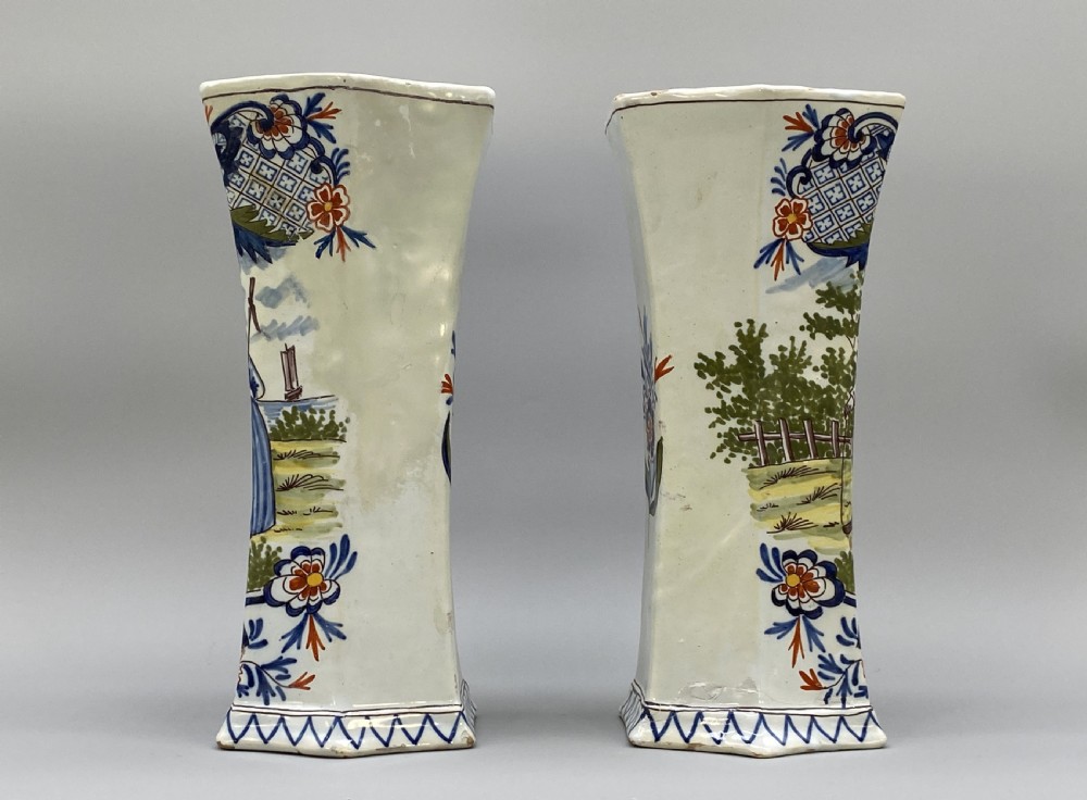 A pair of 18th-century octagonal flared Dutch Delft polychrome tin-glazed earthenware vases featuring hand-painted pastoral scenes of figures in landscape settings framed by floral motifs. View X