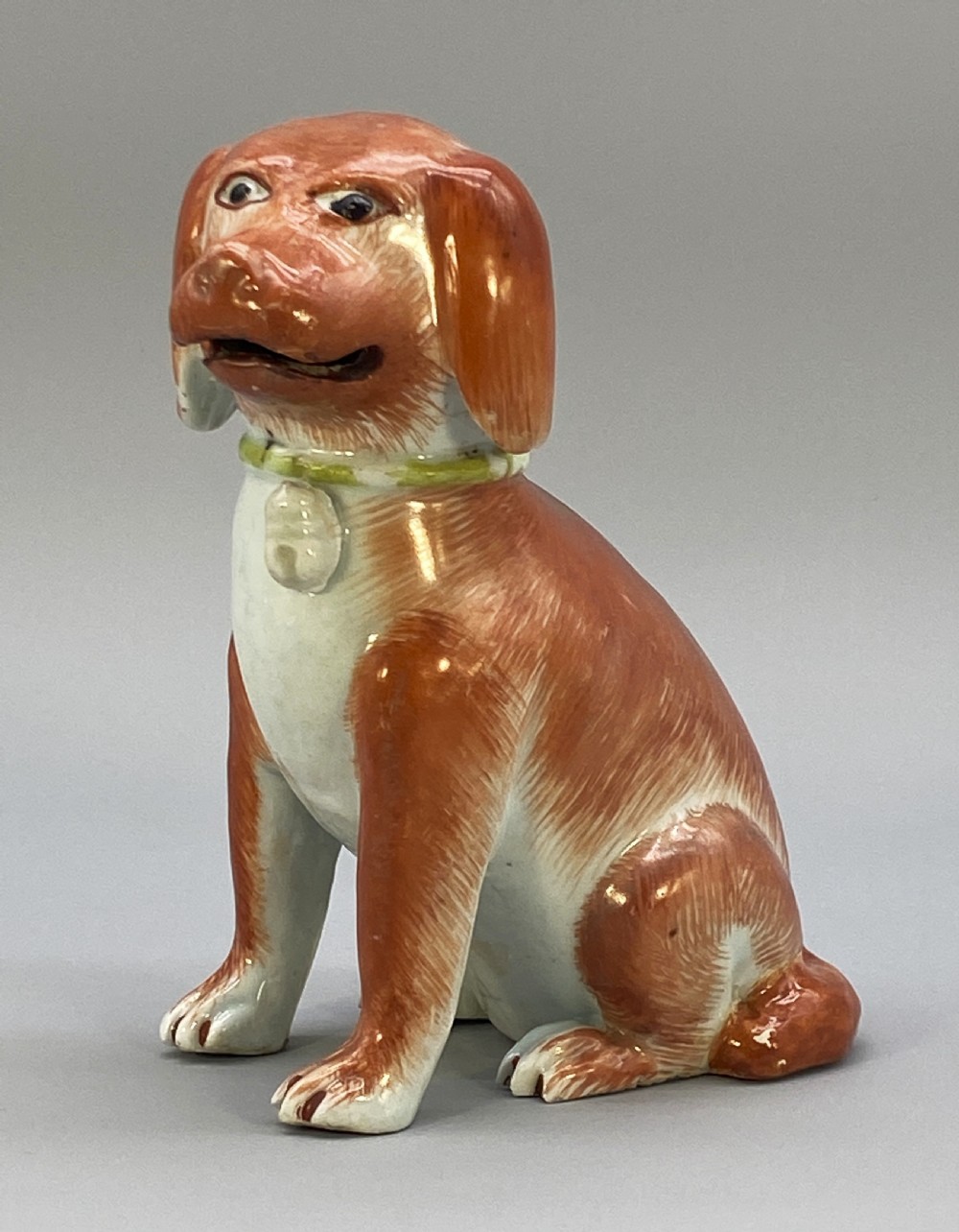 An 18th-century Chinese export porcelain figurine of a seated dog featuring iron-red fur painted details and a light green collar. View XX