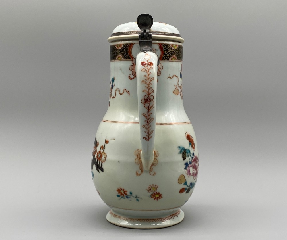 An 18th-century Chinese porcelain jug with hand-painted Famille Rose floral enamels, a metal-mounted lid, and a loop handle. View VII