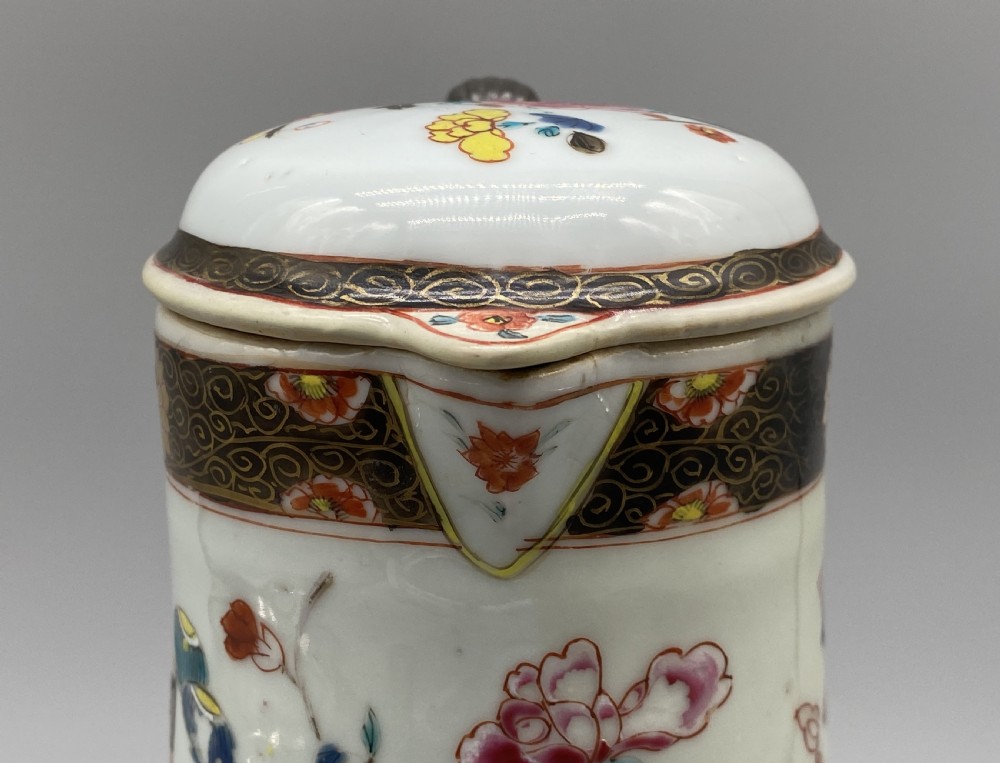 An 18th-century Chinese porcelain jug with hand-painted Famille Rose floral enamels, a metal-mounted lid, and a loop handle. View IX
