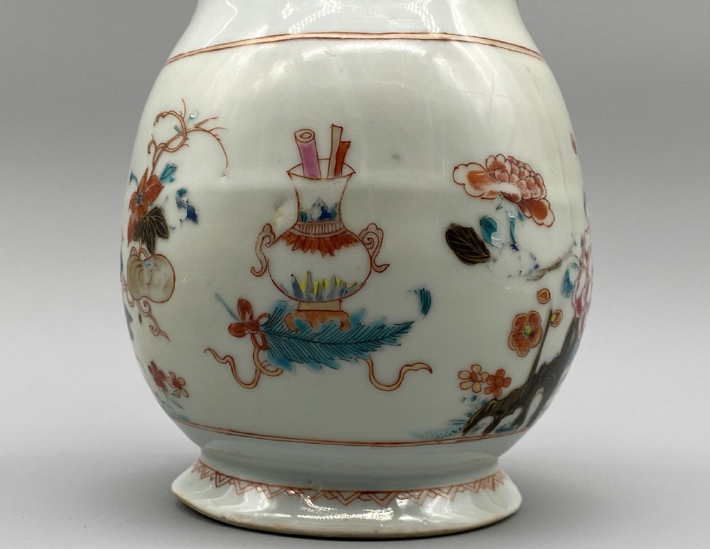 An 18th-century Chinese porcelain jug with hand-painted Famille Rose floral enamels, a metal-mounted lid, and a loop handle. View X
