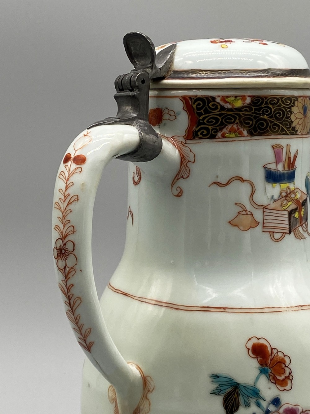 An 18th-century Chinese porcelain jug with hand-painted Famille Rose floral enamels, a metal-mounted lid, and a loop handle. View XIV
