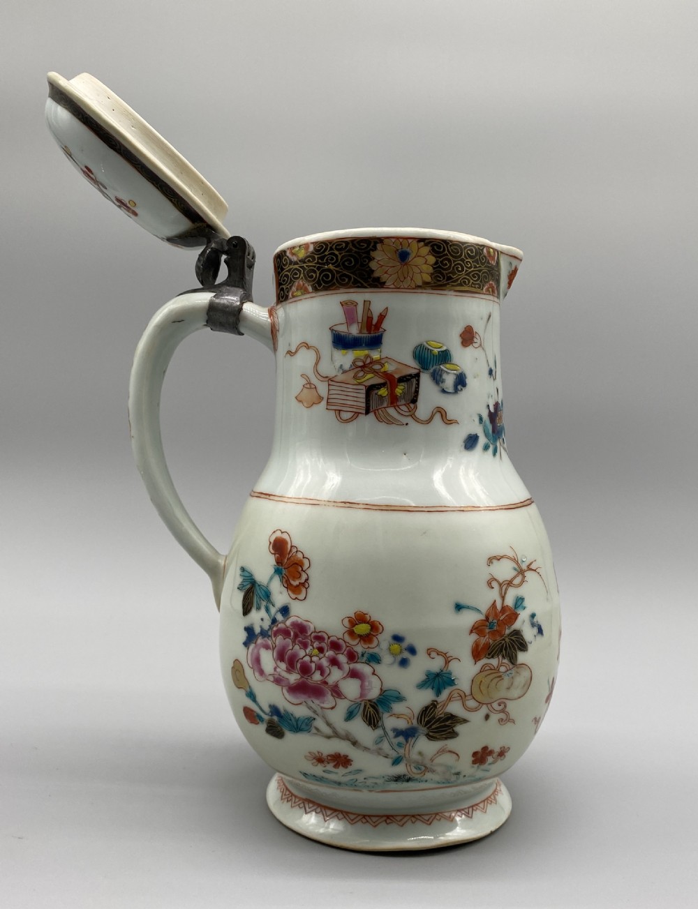 An 18th-century Chinese porcelain jug with hand-painted Famille Rose floral enamels, a metal-mounted lid, and a loop handle. View XV