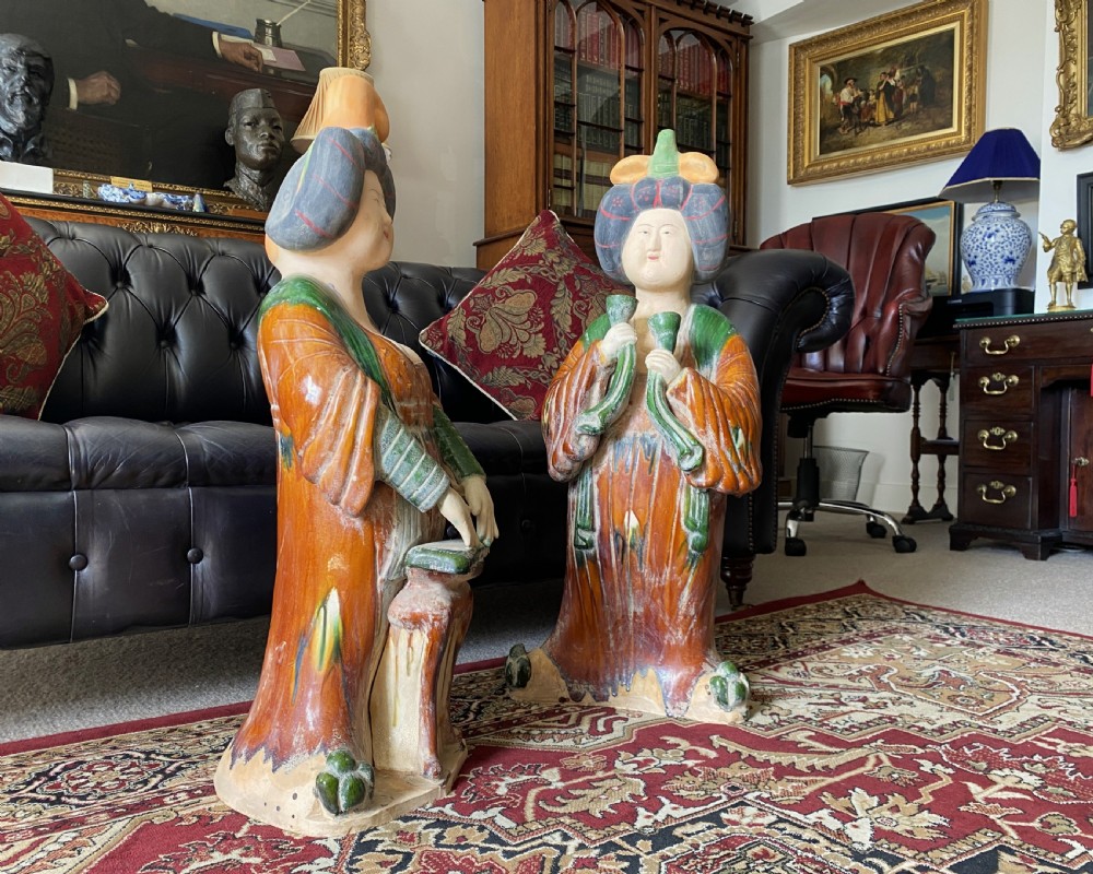 A pair of large Sancai glazed ceramic sculptures depicting Tang Dynasty style female court musicians in orange, green, and cream robes. View III