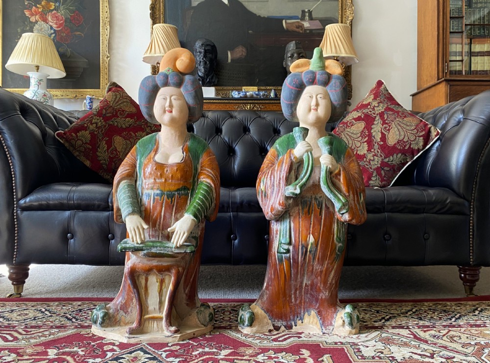 A pair of large Sancai glazed ceramic sculptures depicting Tang Dynasty style female court musicians in orange, green, and cream robes. View V