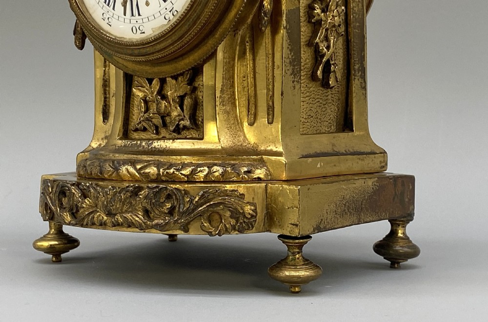 An antique French gilt bronze mantel clock surmounted by two sculpted doves, featuring an ornate pedestal base and a white enamel dial with Roman numerals. View XIII