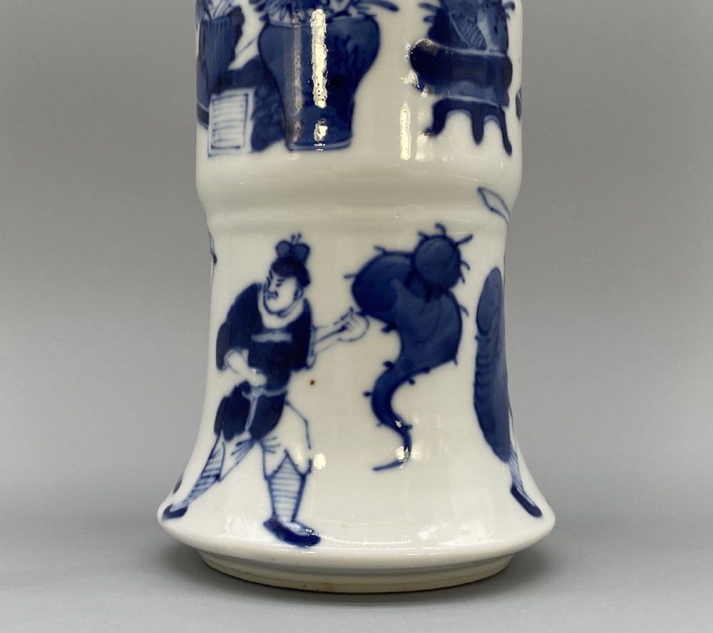 A tall, slender Chinese porcelain beaker vase painted in underglaze cobalt blue featuring equestrian figures and traditional motifs against a smooth white glaze. View VI