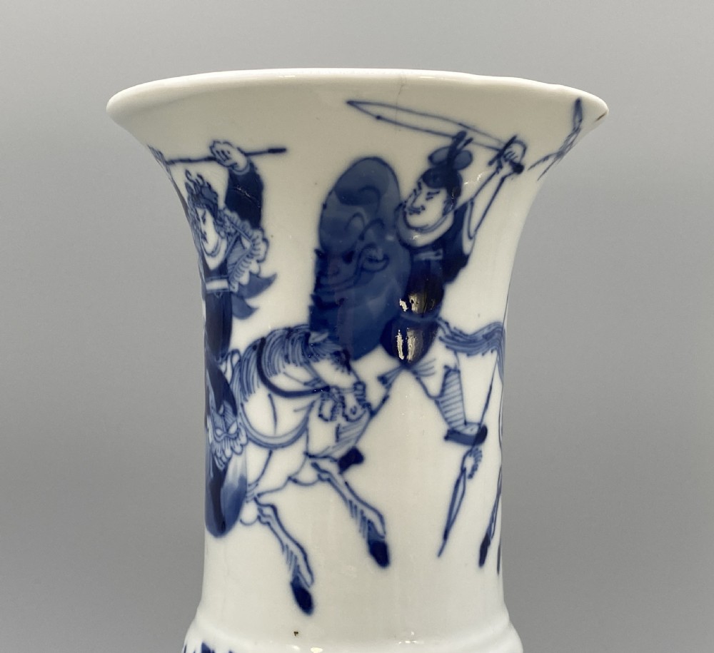 A tall, slender Chinese porcelain beaker vase painted in underglaze cobalt blue featuring equestrian figures and traditional motifs against a smooth white glaze. View VIII