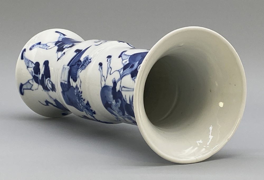 A tall, slender Chinese porcelain beaker vase painted in underglaze cobalt blue featuring equestrian figures and traditional motifs against a smooth white glaze. View XVII