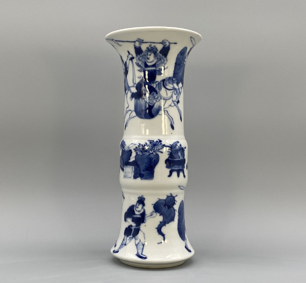 A tall, slender Chinese porcelain beaker vase painted in underglaze cobalt blue featuring equestrian figures and traditional motifs against a smooth white glaze. View XXI