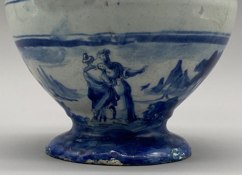 An 18th-century Italian Savona majolica wet drug jar featuring hand-painted cobalt blue landscapes, a single side handle, a raised spout, and a pedestal base. View XI