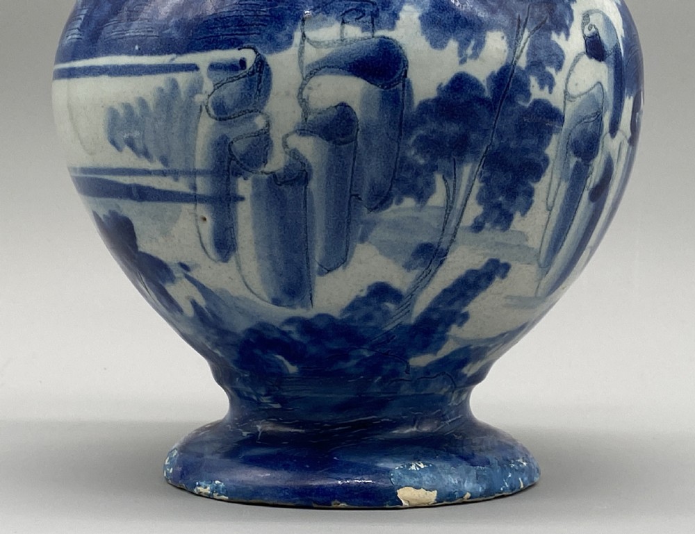 An 18th-century Italian Savona majolica wet drug jar featuring hand-painted cobalt blue landscapes, a single side handle, a raised spout, and a pedestal base. View XIII