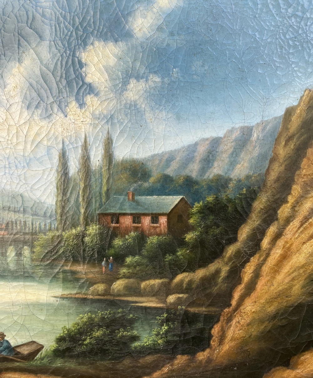 A 19th-century Italian School oil painting depicting a lakeside landscape with figures in a boat, towering cliffs, and a clouded blue sky inside a gilt frame. View V