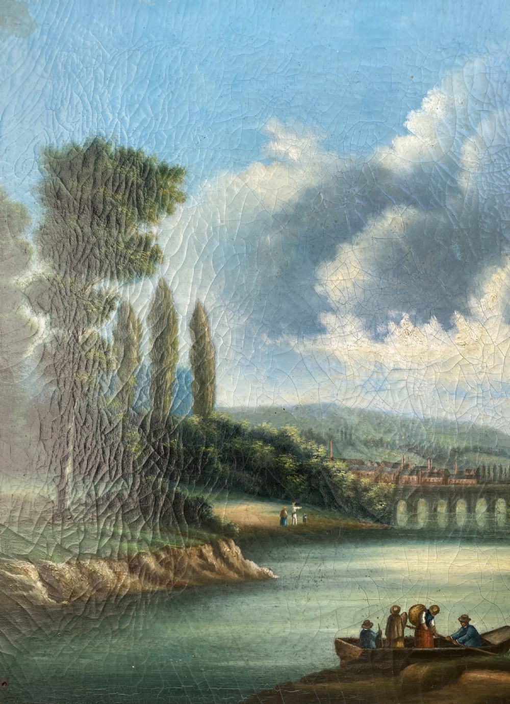 A 19th-century Italian School oil painting depicting a lakeside landscape with figures in a boat, towering cliffs, and a clouded blue sky inside a gilt frame. View IX