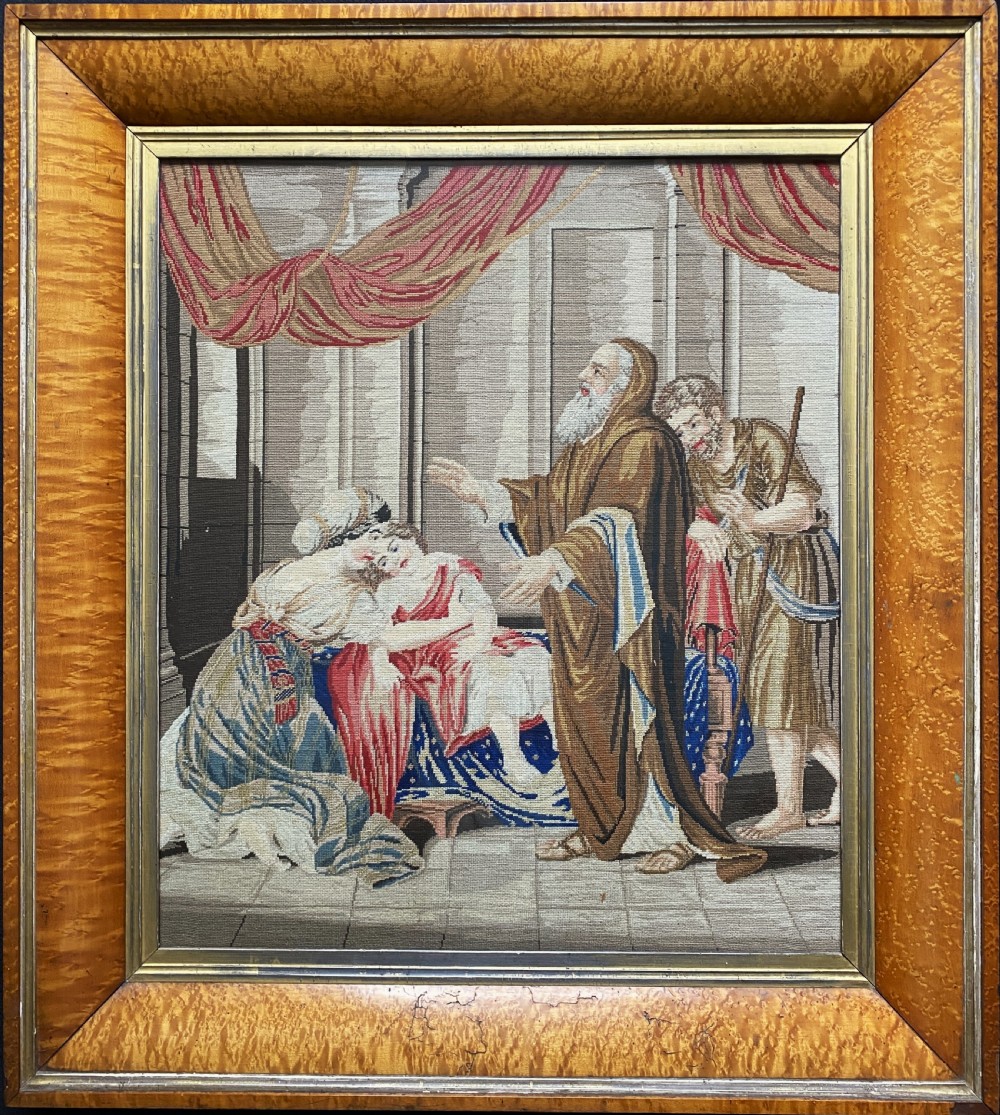 An antique Biedermeier picture frame crafted from birds eye maple veneer with an inner gilt slip enclosing a needlework tapestry.