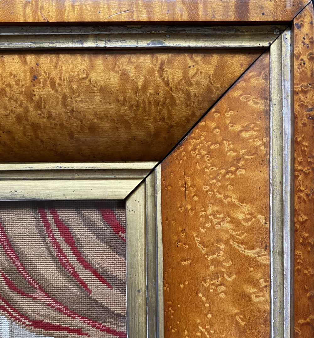 An antique Biedermeier picture frame crafted from birds eye maple veneer with an inner gilt slip enclosing a needlework tapestry. View IV