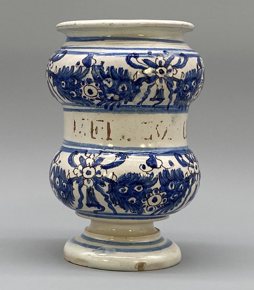 An 18th-century Italian majolica albarello pharmacy jar featuring a waisted silhouette with hand-painted blue floral patterns and central apothecary inscription. View V