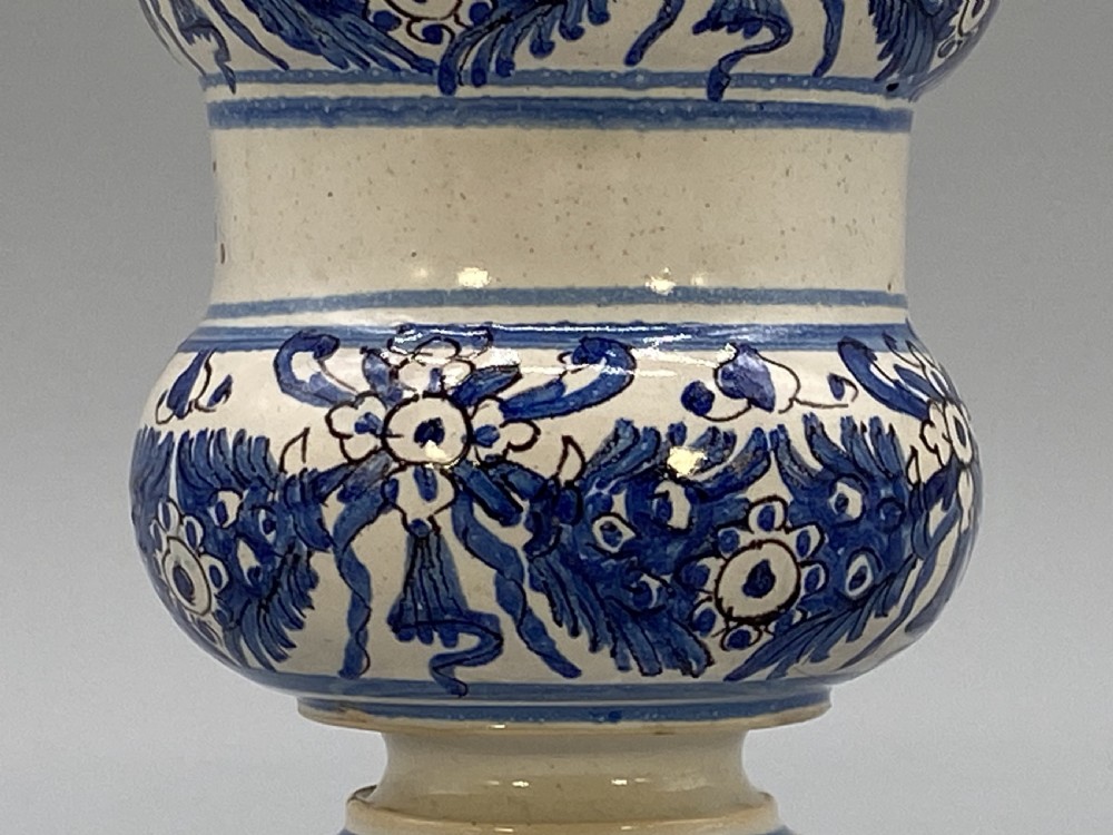An 18th-century Italian majolica albarello pharmacy jar featuring a waisted silhouette with hand-painted blue floral patterns and central apothecary inscription. View X